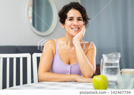 Portrait of woman sitting at a table in her apartment room Portrait of woman sitting at a table in her apartment room 142467794