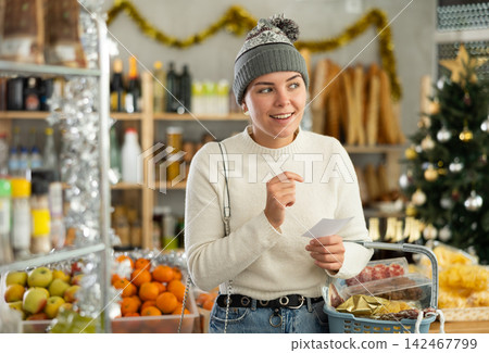 Feale customer prepares to celebrate Christmas - they buy food and alcohol according to checklist at supermarket Feale customer prepares to celebrate Christmas - they buy food and alcohol according to checklist at supermarket 142467799