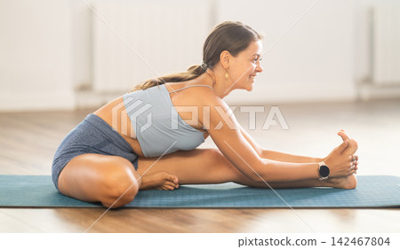 Young girl yoga trainer doing warm-up in yoga studio Young girl yoga trainer doing warm-up in yoga studio 142467804
