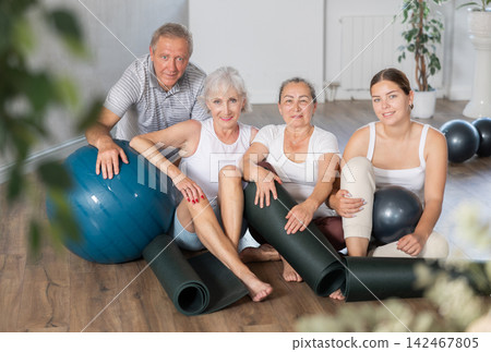 Happy portrait of group of four people with mats and soft balls going to do yoga in gym 142467805