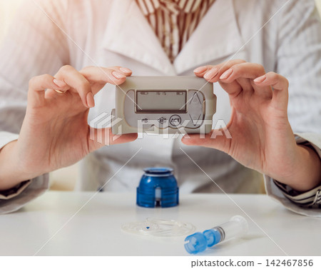 Doctor holding the insulin pump at his hands. Doctor holding the insulin pump at his hands. 142467856