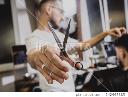 Young man with trendy haircut at barber shop. Barber does the hairstyle and beard trim. Young man with trendy haircut at barber shop. Barber does the hairstyle and beard trim. 142467885
