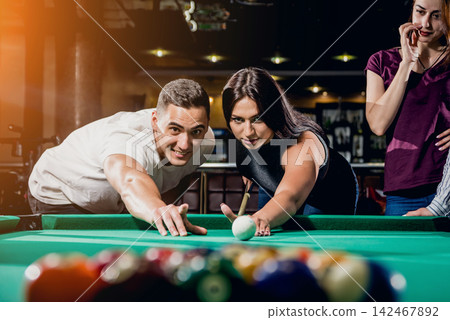Group of young cheerful friends playing billiards. Group of young cheerful friends playing billiards. 142467892