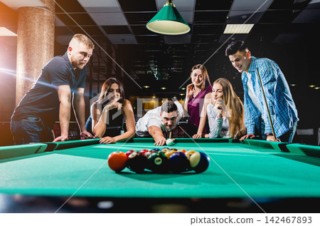 Group of young cheerful friends playing billiards. Group of young cheerful friends playing billiards. 142467893