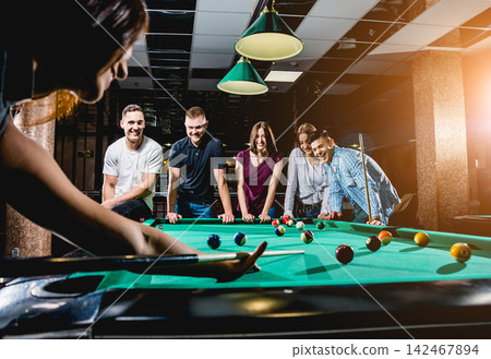 Group of young cheerful friends playing billiards. Group of young cheerful friends playing billiards. 142467894