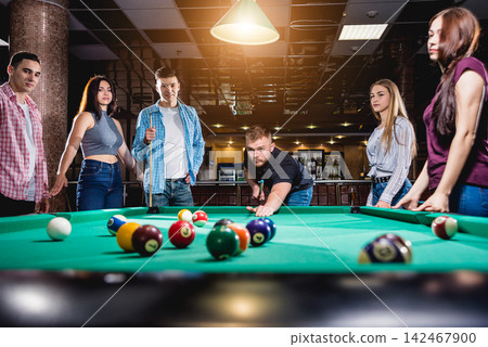 Group of young cheerful friends playing billiards. Group of young cheerful friends playing billiards. 142467900