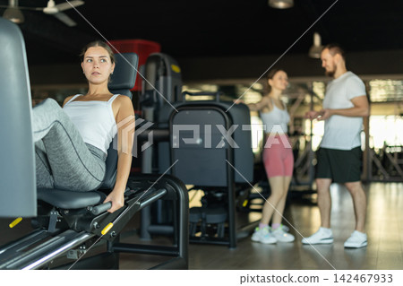 Young woman training her leg muscles on machine Young woman training her leg muscles on machine 142467933