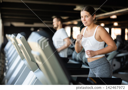 Young woman exercising on treadmill in gym Young woman exercising on treadmill in gym 142467972