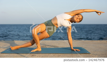Sportive girl practicing wild thing pose of yoga on seashore Sportive girl practicing wild thing pose of yoga on seashore 142467976