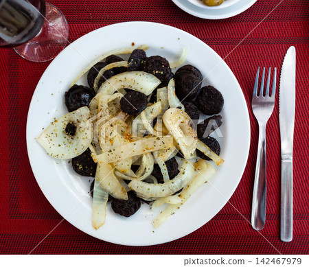 Slices of fried morcilla served with caramelized onions 142467979