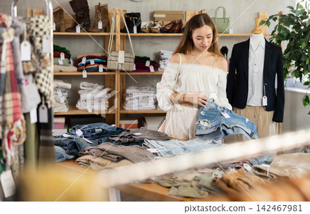 Young woman choosing jean shorts in clothing store Young woman choosing jean shorts in clothing store 142467981