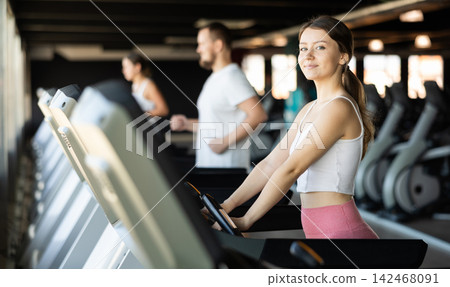 Girl in gym runs with help of treadmill 142468091