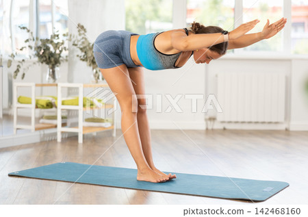 Sporty girl performing powerful dynamic yoga asanas in studio 142468160