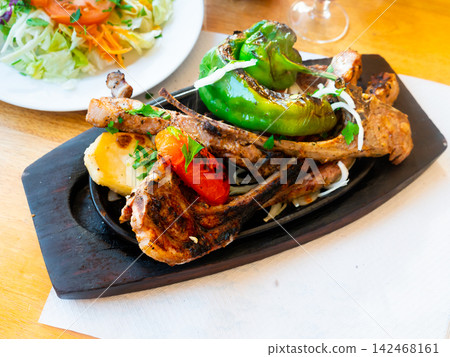 Roasted meaty mutton ribs served on plate with potatoes and baked bell pepper closeup Roasted meaty mutton ribs served on plate with potatoes and baked bell pepper closeup 142468161