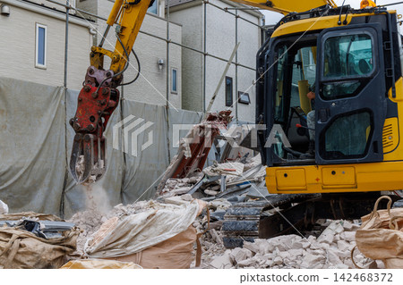 Demolition work on a house and heavy machinery (excavator) in a residential area. Demolition work on a house and heavy machinery (excavator) in a residential area. 142468372