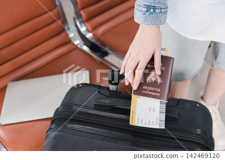 Close up hands woman tourist going to flight with suitcase holding Thailand passport and airline ticket on baggage Close up hands woman tourist going to flight with suitcase holding Thailand passport and airline ticket on baggage 142469120