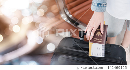 Close up hands woman tourist going to flight with suitcase holding Thailand passport and airline ticket on baggage Close up hands woman tourist going to flight with suitcase holding Thailand passport and airline ticket on baggage 142469123