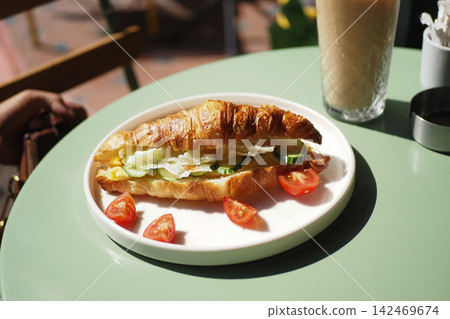 Enjoying a croissant with vegetables and tea Enjoying a croissant with vegetables and tea 142469674