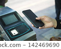 a person using a smartphone for a contactless NFC scan at a public transit turnstile or terminal 142469690