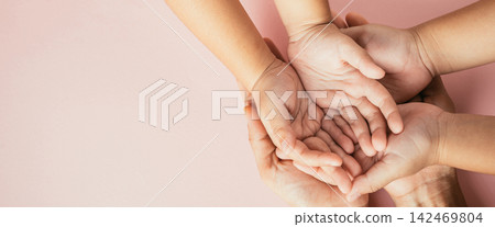 Celebrating family day, Top view of parents and kid holding empty hands together on a color background. Space for text. Celebrating family day, Top view of parents and kid holding empty hands together on a color background. Space for text. 142469804