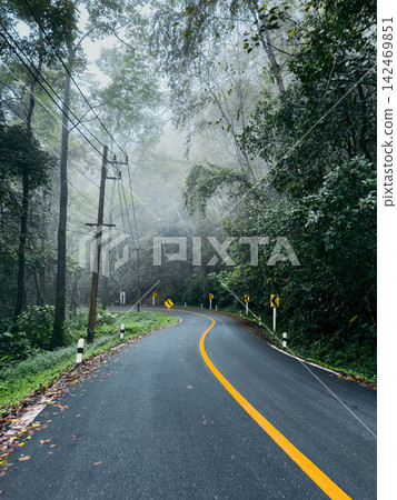 Motion blur perspective of driving on a wet, winding mountain road through a misty forest. Motion blur perspective of driving on a wet, winding mountain road through a misty forest. 142469851