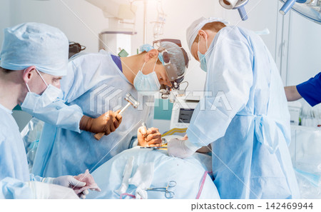 Spinal surgery. Group of surgeons in operating room with surgery equipment. Laminectomy 142469944