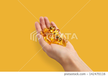 Omega 3. Hand displays softgel capsules of omega fish oil in vibrant setting. Omega 3. Hand displays softgel capsules of omega fish oil in vibrant setting. 142470116