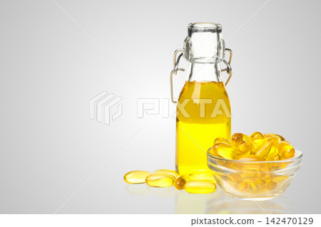 Omega 3. Glass bottle filled with omega fish oil sits beside bowl of capsules. Omega 3. Glass bottle filled with omega fish oil sits beside bowl of capsules. 142470129