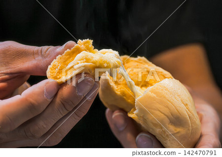 I tore the steaming hot, freshly baked bread apart with both hands. I tore the steaming hot, freshly baked bread apart with both hands. 142470791