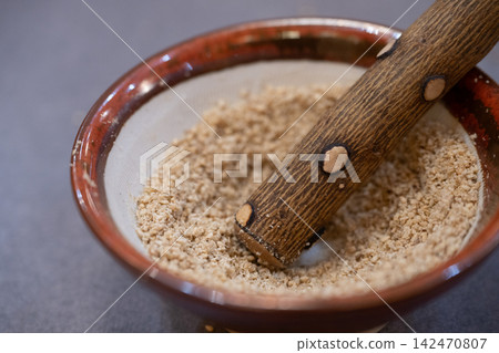 A cooking scene where sesame seeds are ground in a mortar. A cooking scene where sesame seeds are ground in a mortar. 142470807