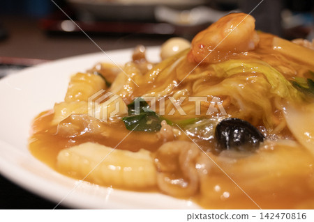 一盤熱騰騰的海鮮炒麵,淋上濃稠的醬汁。 一盤熱騰騰的海鮮炒麵,淋上濃稠的醬汁。 142470816
