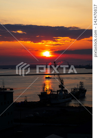 A bright red sunset sinking into an industrial area, and a view of the harbor. A bright red sunset sinking into an industrial area, and a view of the harbor. 142470817