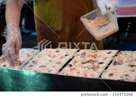在食品攤位上，將海鮮餡麵團放在鐵板上煎熟，然後加入食材。 142471098