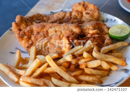 A platter of fried fish and potatoes with lime. A platter of fried fish and potatoes with lime. 142471107