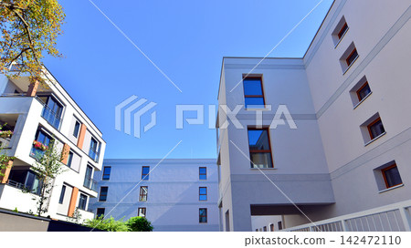 European residential architecture harmonizing with nature. Eco-friendly living in city with greens. Eco apartment building saving energy and fresh air concept. European residential architecture harmonizing with nature. Eco-friendly living in city with greens. Eco apartment building saving energy and fresh air concept. 142472110