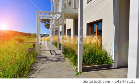 European residential architecture harmonizing with nature. Eco-friendly living in city with greens. Eco apartment building saving energy and fresh air concept. European residential architecture harmonizing with nature. Eco-friendly living in city with greens. Eco apartment building saving energy and fresh air concept. 142472123