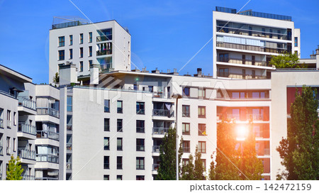 European residential architecture harmonizing with nature. Eco-friendly living in city with greens. Eco apartment building saving energy and fresh air concept. European residential architecture harmonizing with nature. Eco-friendly living in city with greens. Eco apartment building saving energy and fresh air concept. 142472159