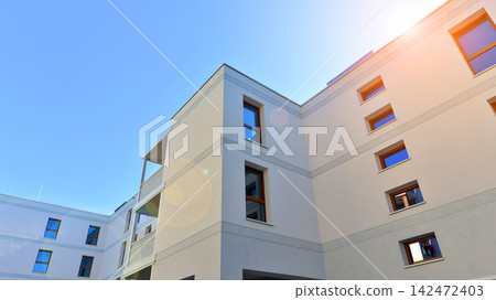 Modern apartment buildings on a sunny day with a blue sky. Facade of a modern apartment building. Glass surface with sunlight. Modern apartment buildings on a sunny day with a blue sky. Facade of a modern apartment building. Glass surface with sunlight. 142472403