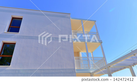 Modern apartment buildings on a sunny day with a blue sky. Facade of a modern apartment building. Glass surface with sunlight. Modern apartment buildings on a sunny day with a blue sky. Facade of a modern apartment building. Glass surface with sunlight. 142472412