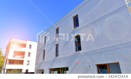 Modern apartment buildings on a sunny day with a blue sky. Facade of a modern apartment building. Glass surface with sunlight. Modern apartment buildings on a sunny day with a blue sky. Facade of a modern apartment building. Glass surface with sunlight. 142472414