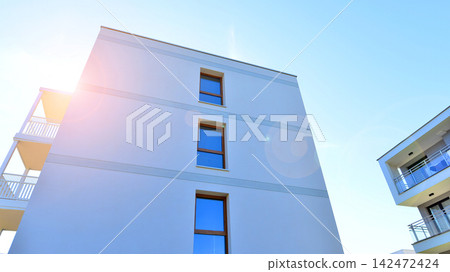 Modern apartment buildings on a sunny day with a blue sky. Facade of a modern apartment building. Glass surface with sunlight. Modern apartment buildings on a sunny day with a blue sky. Facade of a modern apartment building. Glass surface with sunlight. 142472424