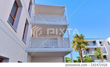 Modern apartment buildings on a sunny day with a blue sky. Facade of a modern apartment building. Glass surface with sunlight. Modern apartment buildings on a sunny day with a blue sky. Facade of a modern apartment building. Glass surface with sunlight. 142472426