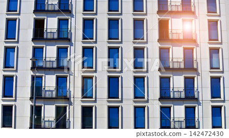 Modern apartment buildings on a sunny day with a blue sky. Facade of a modern apartment building. Glass surface with sunlight. Modern apartment buildings on a sunny day with a blue sky. Facade of a modern apartment building. Glass surface with sunlight. 142472430