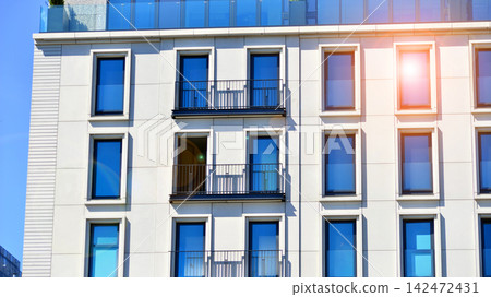 Modern apartment buildings on a sunny day with a blue sky. Facade of a modern apartment building. Glass surface with sunlight. Modern apartment buildings on a sunny day with a blue sky. Facade of a modern apartment building. Glass surface with sunlight. 142472431