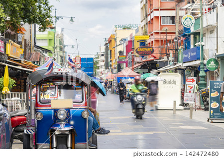 泰國曼谷熙熙攘攘的考山路,以及一輛停著的嘟嘟車。 泰國曼谷熙熙攘攘的考山路,以及一輛停著的嘟嘟車。 142472480