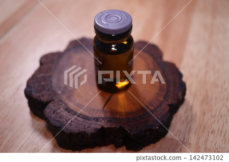 Amber Glass Bottle on Wooden Slice Base Amber Glass Bottle on Wooden Slice Base 142473102