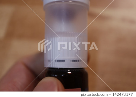 Close-Up of Hand Holding Small Bottle with White Cap Close-Up of Hand Holding Small Bottle with White Cap 142473177