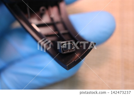 Close-up of electronic device component in gloved hand 142473237