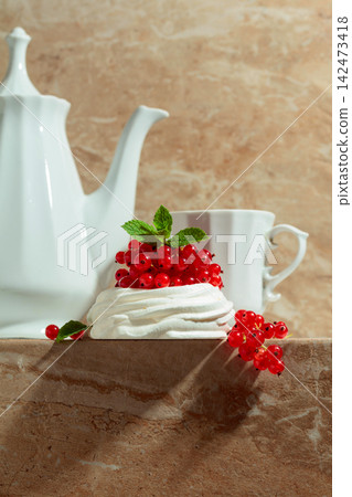 Pavlova dessert with red currant, and mint on a beige table. Pavlova dessert with red currant, and mint on a beige table. 142473418