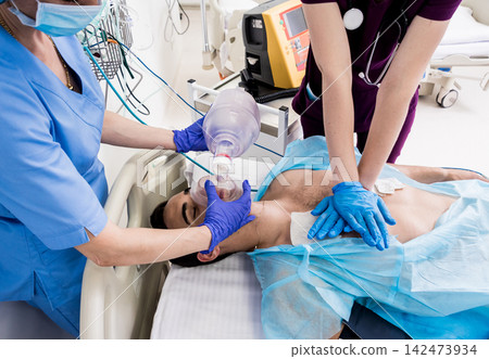 Doctors give resuscitation to a male patient in the emergency room. Cardiac massage Doctors give resuscitation to a male patient in the emergency room. Cardiac massage 142473934